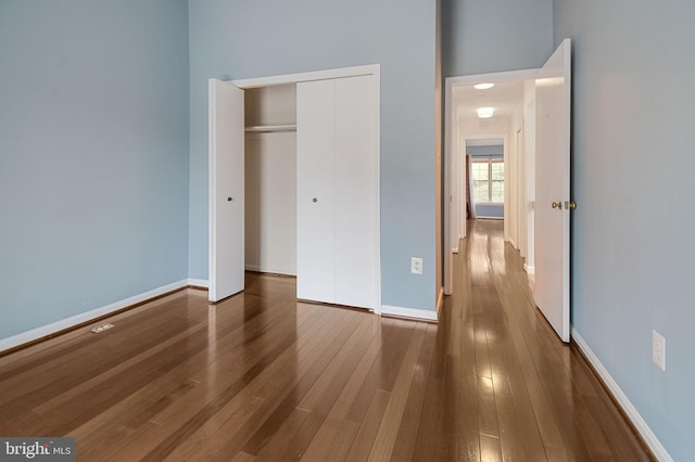 unfurnished bedroom featuring a closet, baseboards, and wood finished floors