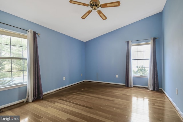 unfurnished room featuring vaulted ceiling, wood finished floors, a ceiling fan, and baseboards