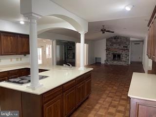 kitchen featuring a large fireplace, lofted ceiling, open floor plan, light countertops, and ornate columns