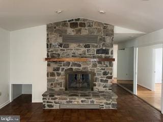 unfurnished living room featuring a fireplace, vaulted ceiling, and dark wood-type flooring