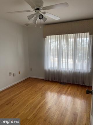 spare room featuring plenty of natural light, baseboards, and wood finished floors