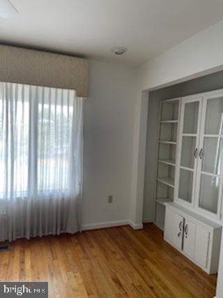 unfurnished room featuring light wood-type flooring, radiator, and baseboards