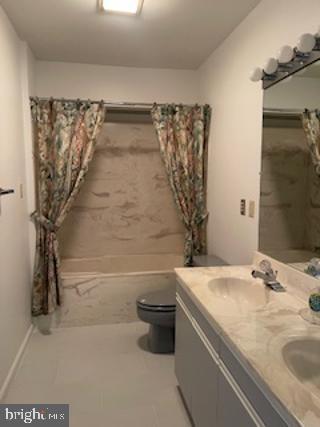 bathroom featuring shower / bath combination with curtain, a sink, toilet, and double vanity