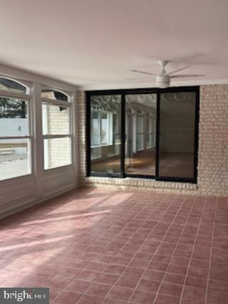 unfurnished sunroom with a ceiling fan