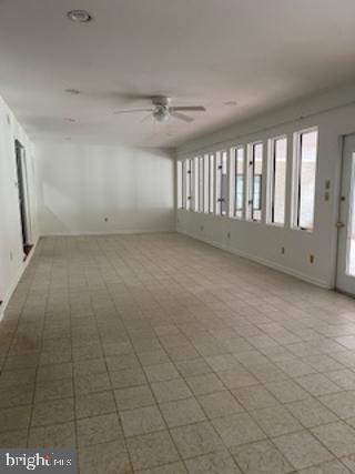 empty room featuring a ceiling fan and baseboards