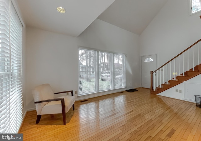 foyer entrance with wood-type flooring, stairs, high vaulted ceiling, and baseboards