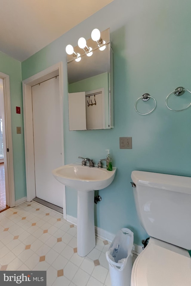 bathroom with baseboards, a sink, toilet, and tile patterned floors