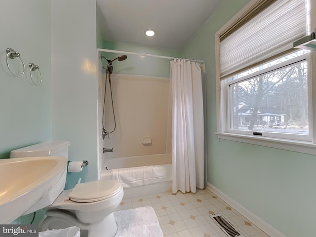 full bathroom featuring toilet, shower / tub combo, a sink, visible vents, and baseboards