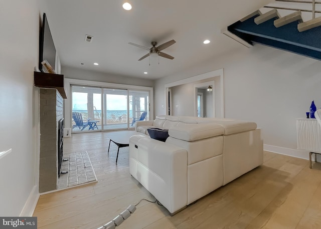 living room with recessed lighting, a fireplace, visible vents, baseboards, and light wood-style floors