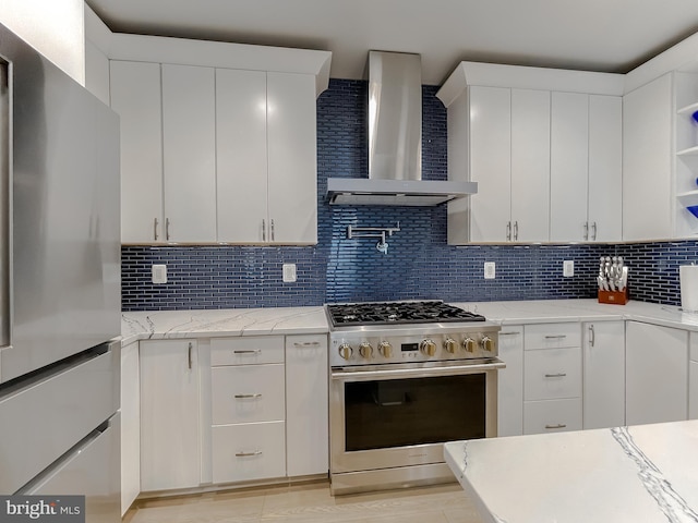 kitchen with appliances with stainless steel finishes, open shelves, wall chimney exhaust hood, and tasteful backsplash