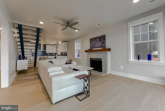 living area featuring recessed lighting, a fireplace, a ceiling fan, baseboards, and light wood-style floors