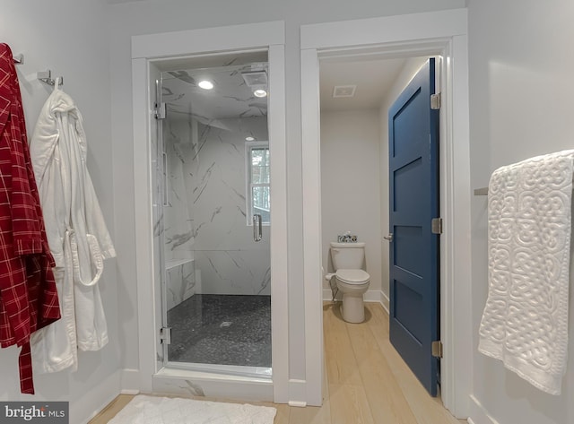 full bathroom featuring toilet, wood finished floors, visible vents, baseboards, and a marble finish shower