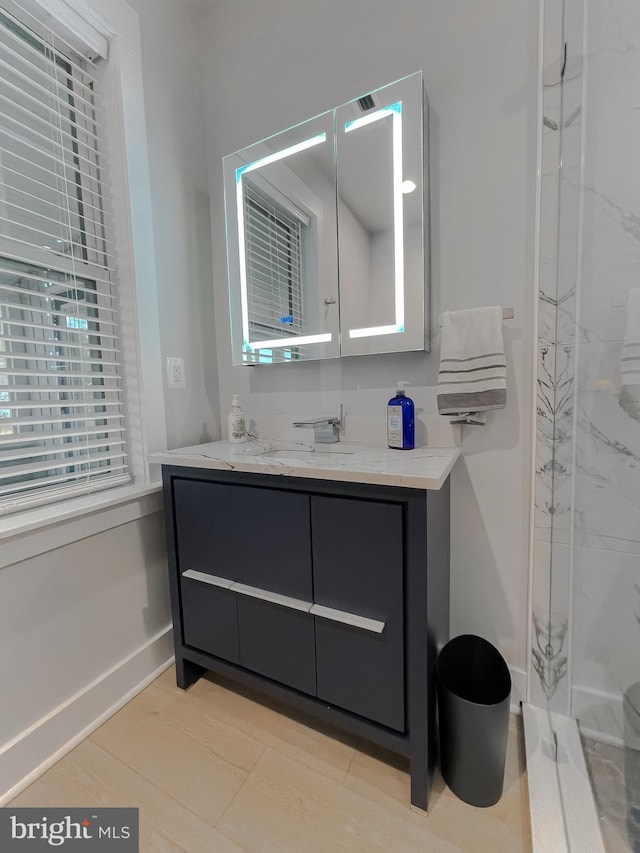 bathroom with vanity, baseboards, and walk in shower