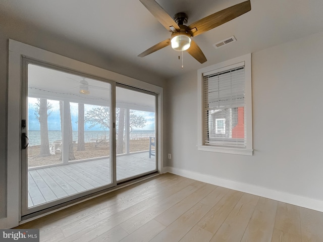 empty room with ceiling fan, wood finished floors, visible vents, and baseboards