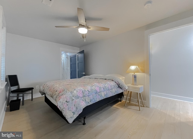 bedroom featuring a ceiling fan, light wood-type flooring, visible vents, and baseboards