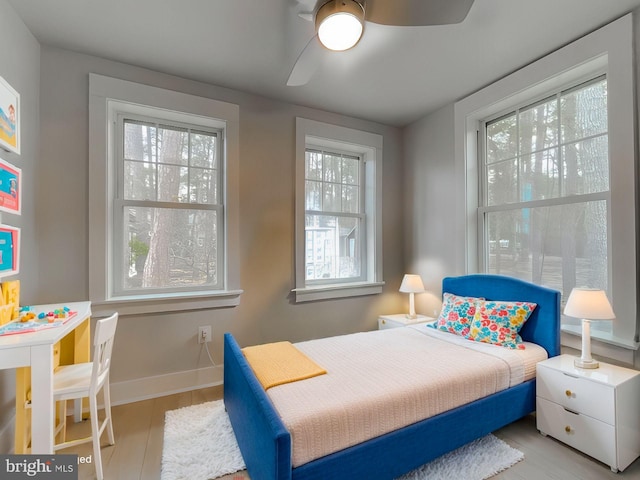 bedroom featuring ceiling fan, multiple windows, and baseboards