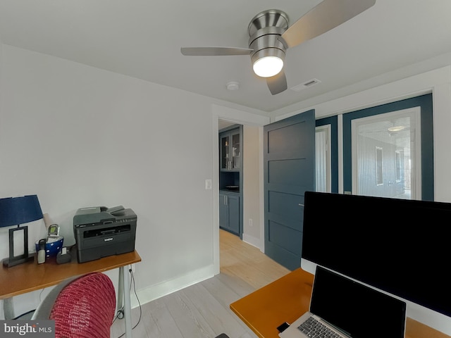 office area featuring a ceiling fan, baseboards, visible vents, and light wood finished floors