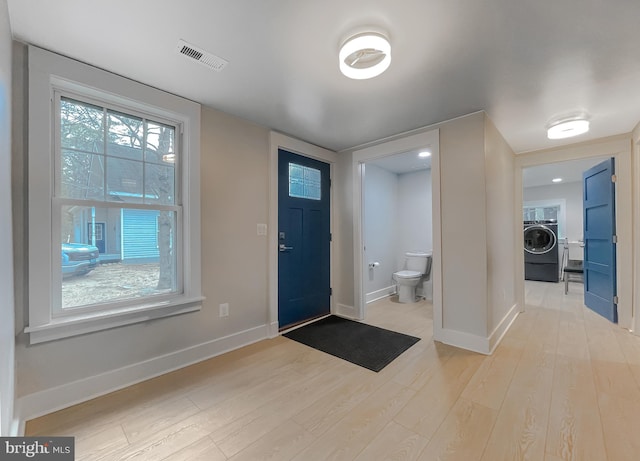 entrance foyer with washer / dryer, light wood-style flooring, visible vents, and baseboards