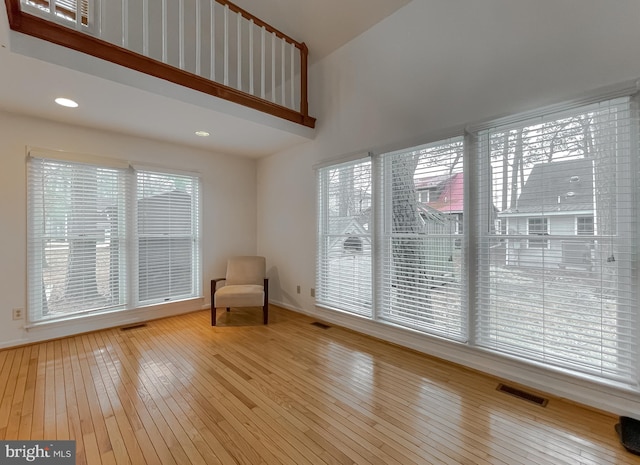 unfurnished room featuring a towering ceiling, visible vents, and hardwood / wood-style floors