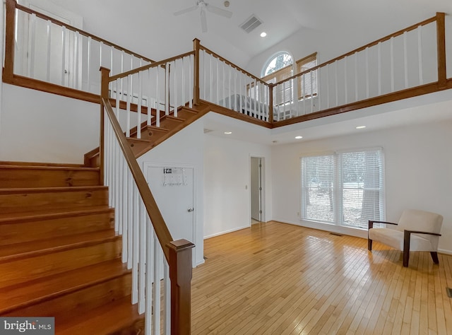 stairs with visible vents, a ceiling fan, high vaulted ceiling, baseboards, and hardwood / wood-style flooring