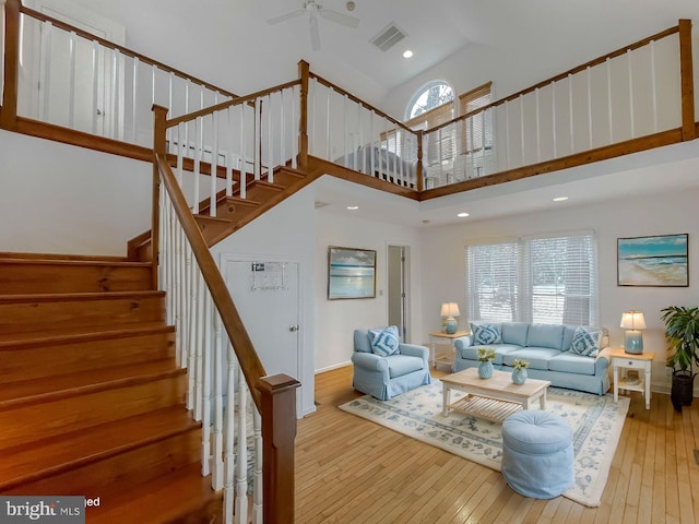 living area with high vaulted ceiling, visible vents, hardwood / wood-style floors, and stairs