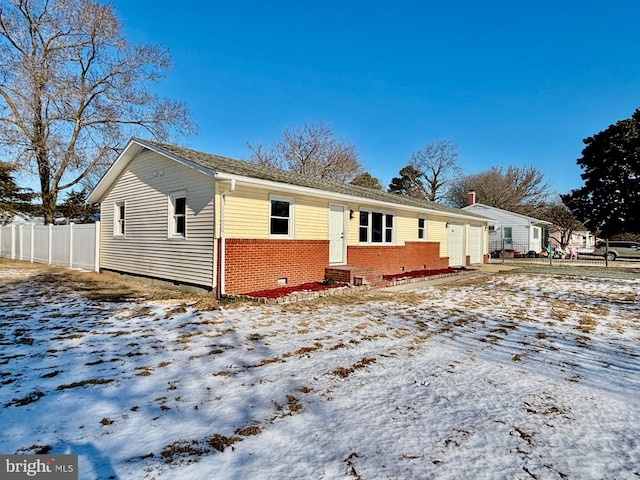 view of front of home with brick siding, crawl space, and fence