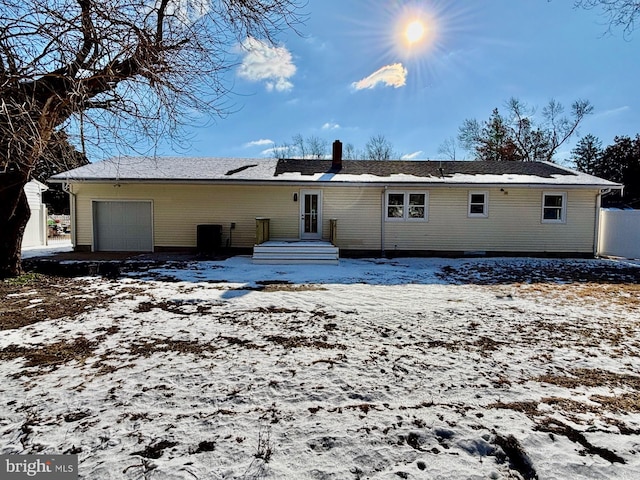 snow covered rear of property featuring a garage