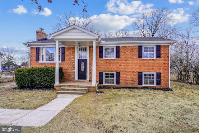 view of front facade featuring brick siding, a chimney, and a front lawn