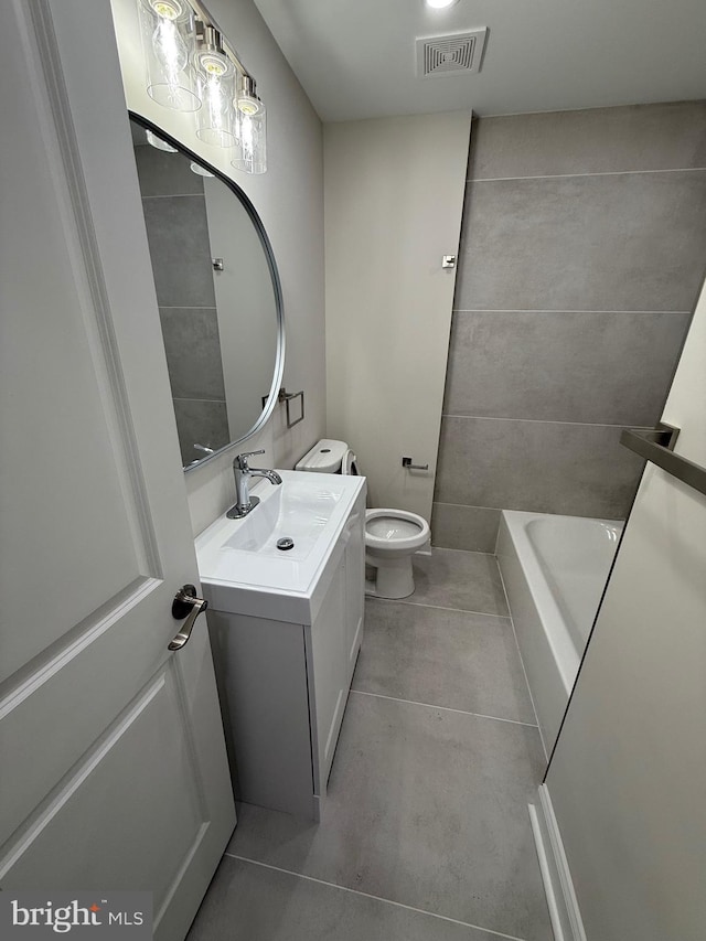 bathroom with visible vents, toilet, tile patterned floors, a washtub, and vanity