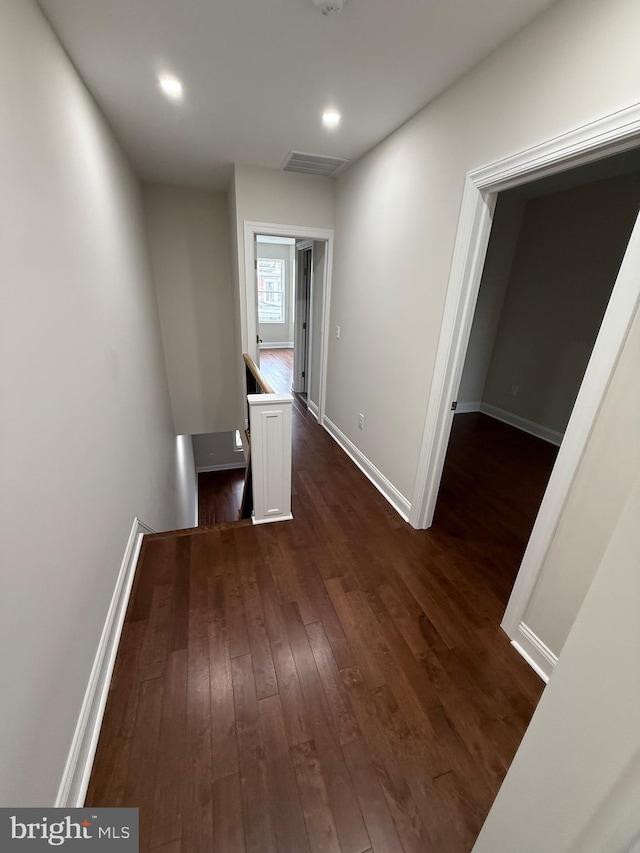 hallway with dark wood-style flooring, recessed lighting, visible vents, an upstairs landing, and baseboards