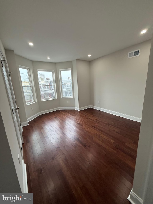 spare room featuring baseboards, dark wood-style flooring, visible vents, and recessed lighting