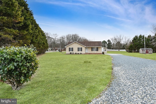 view of front of house featuring driveway, a front lawn, and a shed