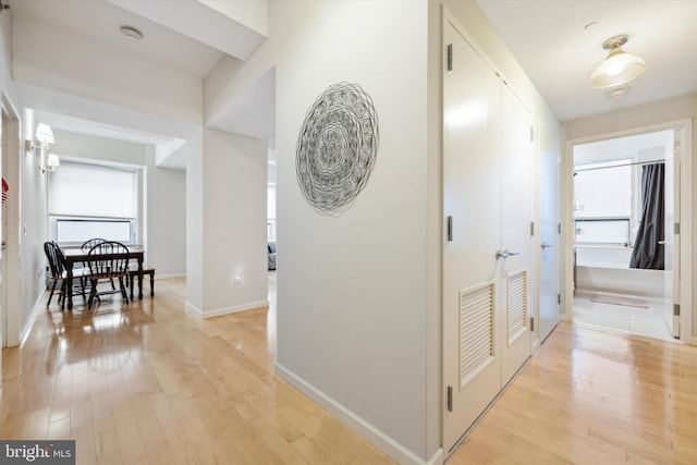 hallway featuring light wood-type flooring and baseboards