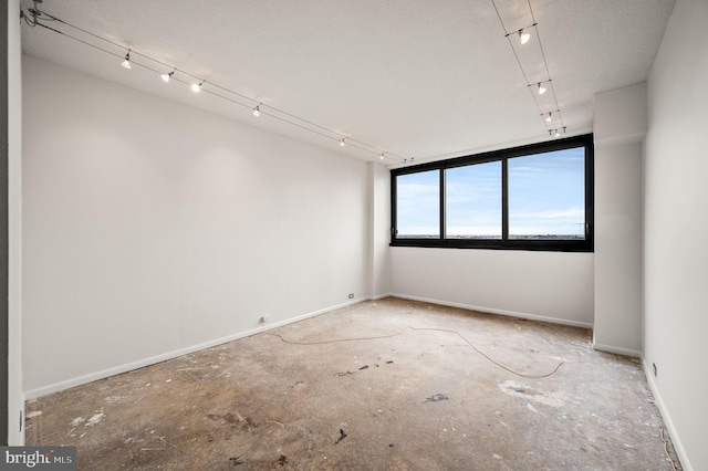 empty room featuring baseboards and track lighting