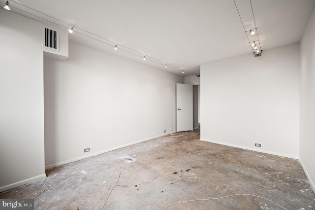 empty room with visible vents, baseboards, and track lighting