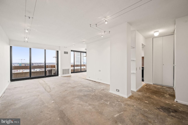 unfurnished room featuring rail lighting, visible vents, unfinished concrete flooring, and baseboards