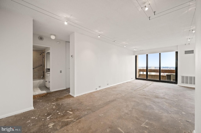 spare room featuring baseboards, visible vents, and track lighting