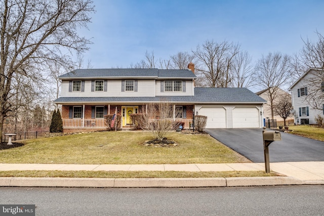 view of front of home featuring aphalt driveway, a front yard, covered porch, and brick siding