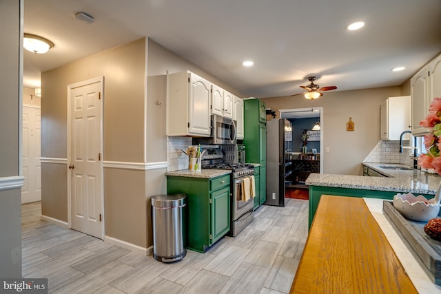 kitchen with stainless steel appliances, wood tiled floor, white cabinetry, and a sink