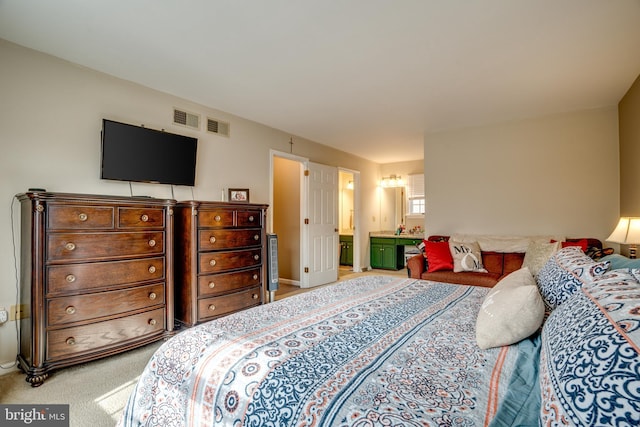 carpeted bedroom featuring ensuite bath and visible vents