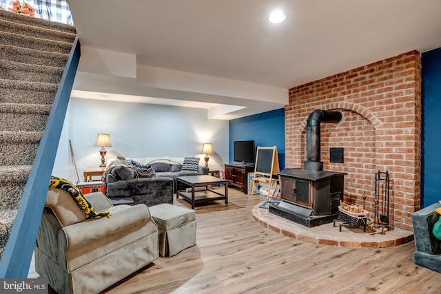 living area featuring a wood stove, stairs, and wood finished floors