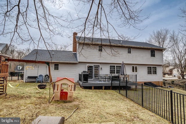 back of house with a playground, a chimney, a lawn, a fenced backyard, and a wooden deck