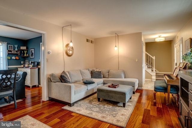 living area with a wealth of natural light, stairway, dark wood finished floors, and visible vents