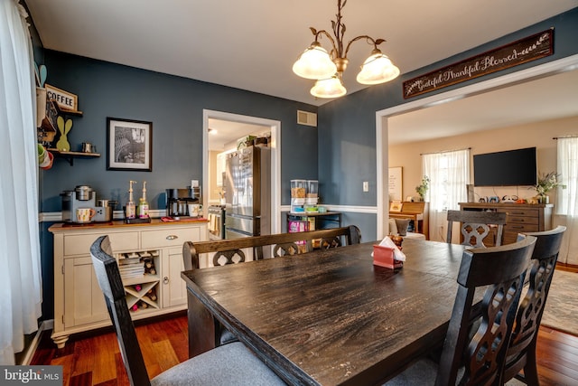 dining space featuring a chandelier, dark wood-style flooring, and visible vents