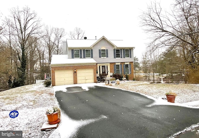 colonial-style house with driveway and brick siding