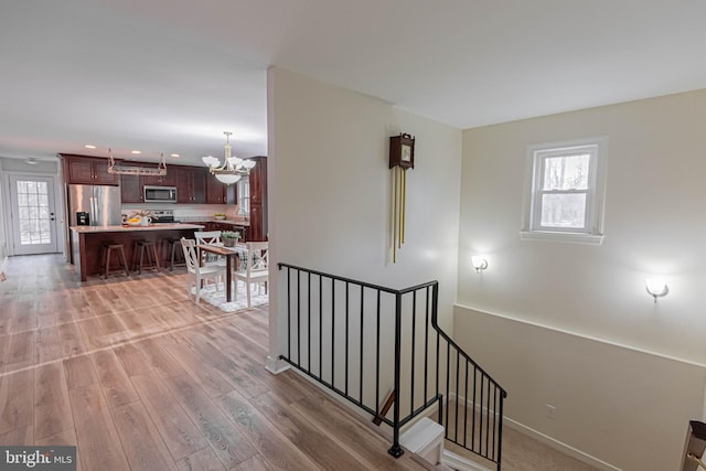 staircase with wood finished floors, baseboards, plenty of natural light, and a chandelier