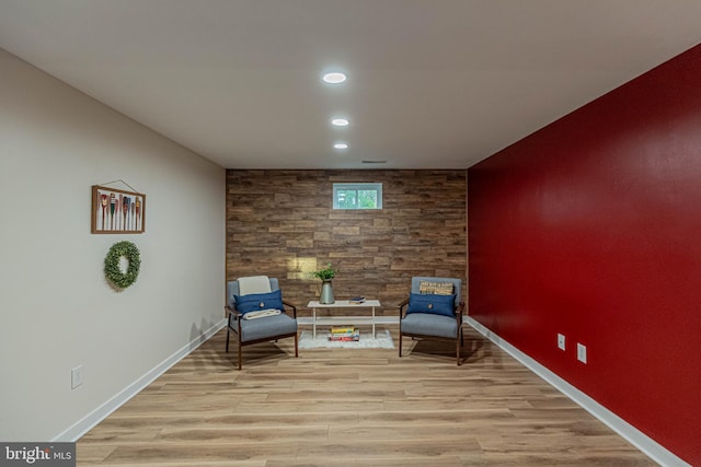 sitting room featuring recessed lighting, light wood-style flooring, an accent wall, and baseboards