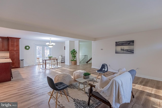 living area featuring light wood-type flooring, baseboards, and a notable chandelier