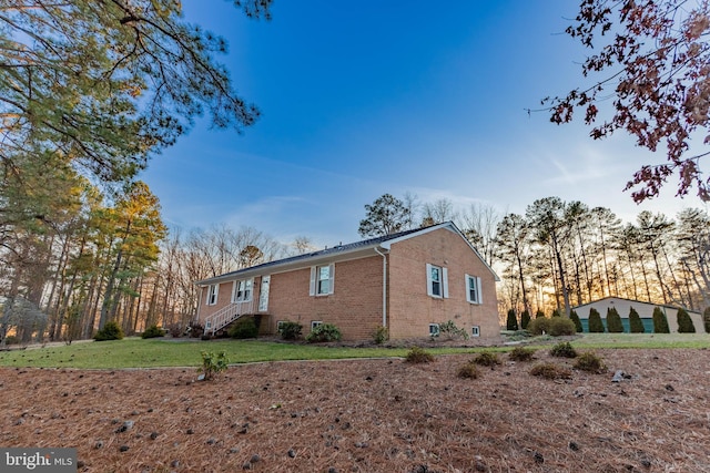 view of property exterior featuring a lawn, brick siding, and a chimney