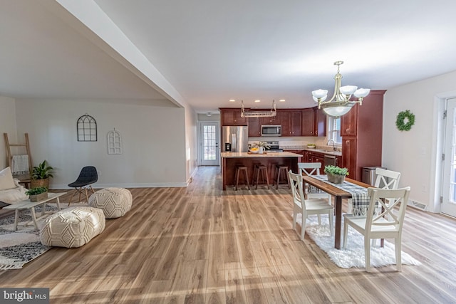 dining area with light wood finished floors, baseboards, and an inviting chandelier